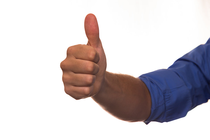man wears blue dress shirt while doing thumbs up