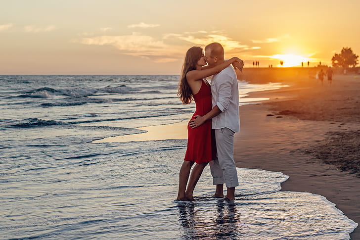 man and woman standing on seashore during daytime