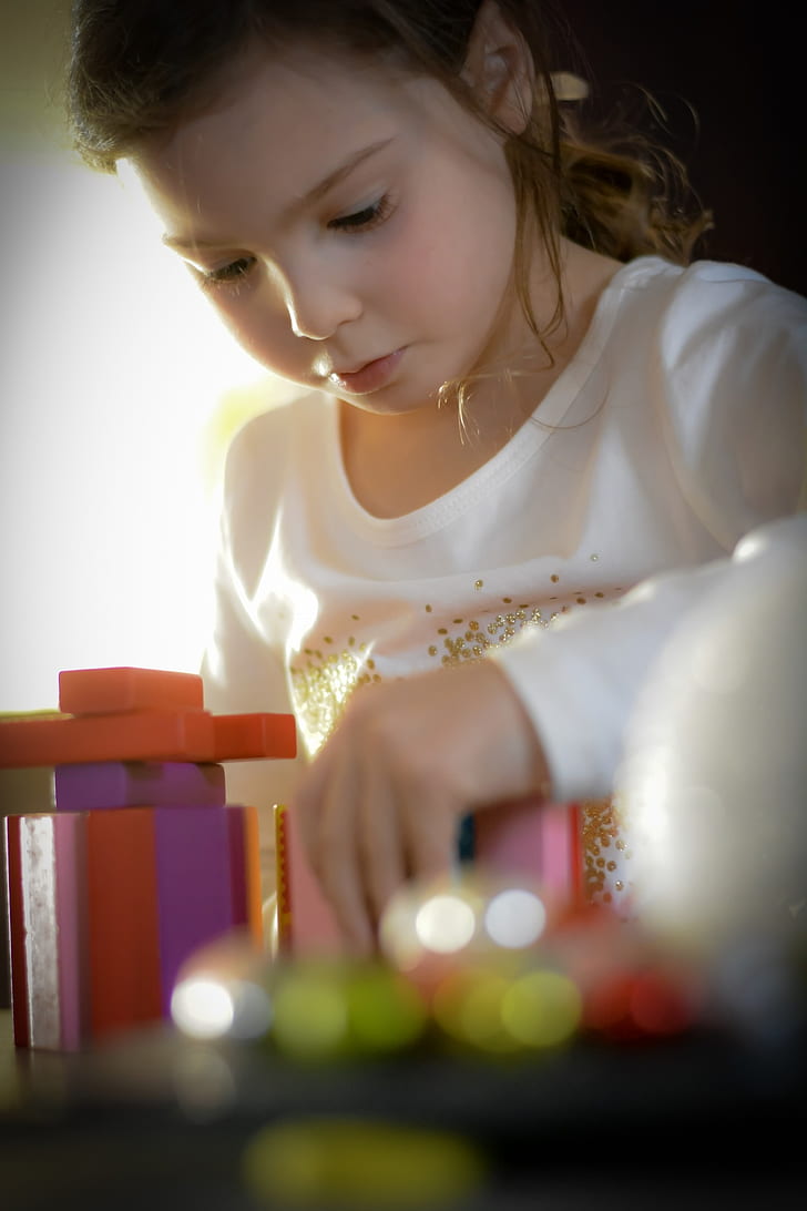 girl in white long-sleeved shirt playing toy