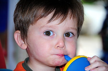 boy sipping on blue and yellow sippy cup