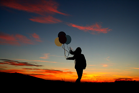 silhouette of woman holding balloons