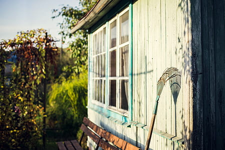 blue and brown garden rake leaning on white wooden wall during daytime