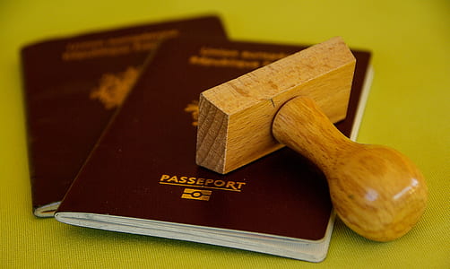 brown wooden stamp and two maroon passport