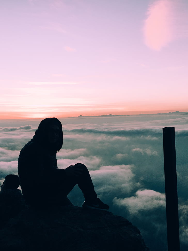 silhouette of person sitting under purple sky