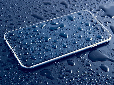 silver iPhone X filled with water droplets on black surface