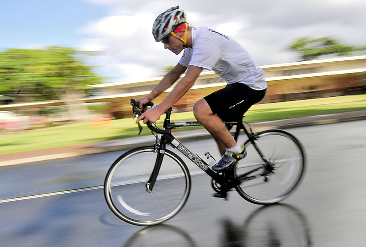 man wearing white t-shirt and black shorts on bike in time laps photography