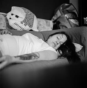 woman wearing white cap-sleeved shirt sleeping on sofa