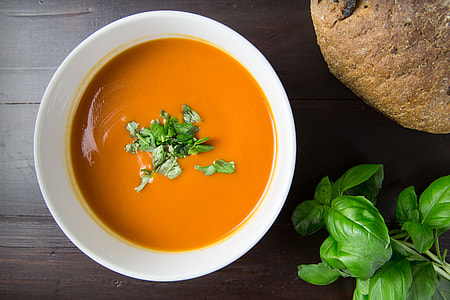 Bowl of tomato soup with basil and walnut bread