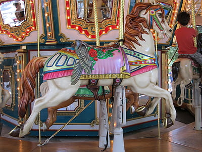 boy riding on white and brown horse carousel