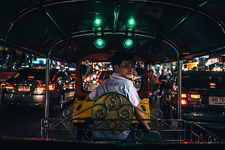 man in white polo shirt driving black and yellow auto rickshaw