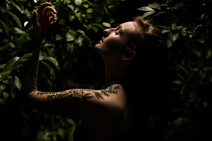 Woman with tattoos in plant foliage