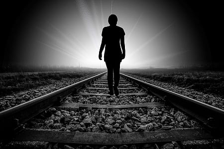 silhouette of person waling on railway