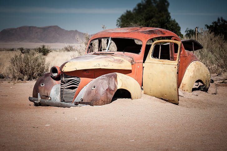 photo of vintage red car on brown sand
