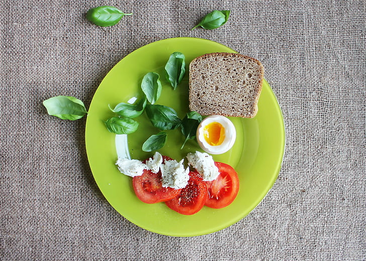 slice tomato with egg and bread on green plate