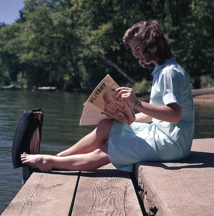 woman sitting on dock holding Playboy magazine