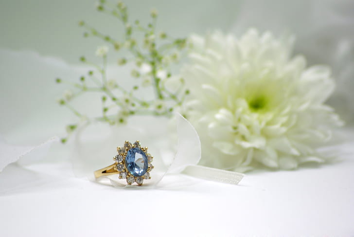 gold-colored blue stone encrusted ring beside white flower