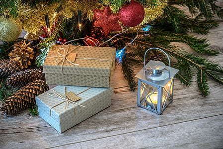 two grey gift boxes beside grey candle lantern and pinecones