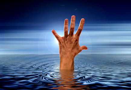 photo of human hand on body of water