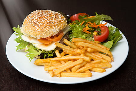 hamburger and fries with sliced tomato and lettuce filled white plate