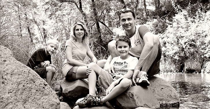 grayscale photo of woman, man, and two boys by water stream