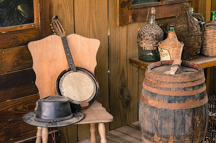 cowboy hat and string instrument on chair beside wine barrel