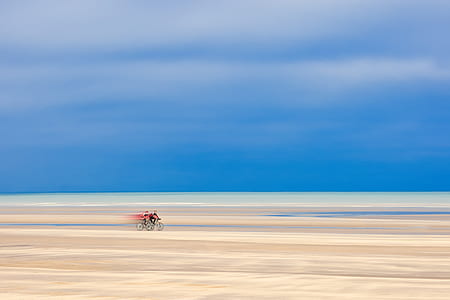 two person biking on brown sand surface painting