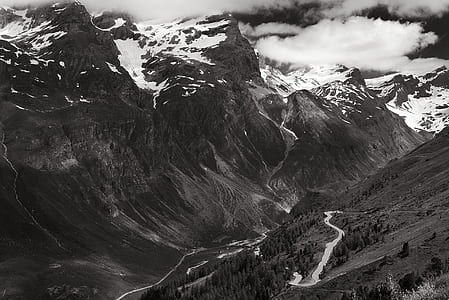 Greyscale Photo of Mountains Surrounded by Clouds