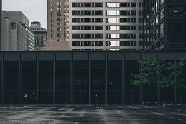 man walking beside gray building