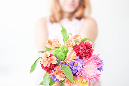 shallow focus photography of woman holding assorted flower bouquet