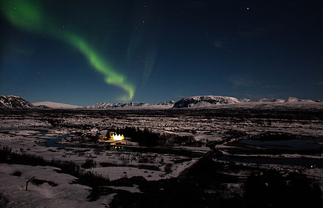 aurora on sky during night time above trees and mountains
