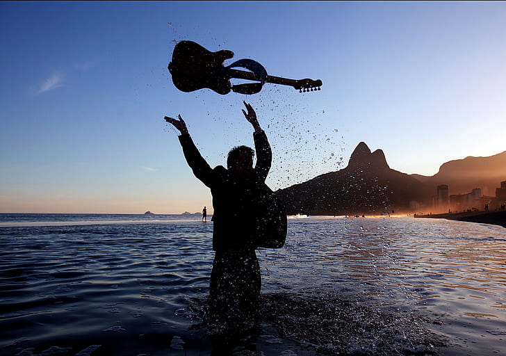 person in water throwing guitar
