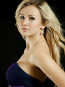 photo of woman wearing blue sweetheart neckline dress with black background