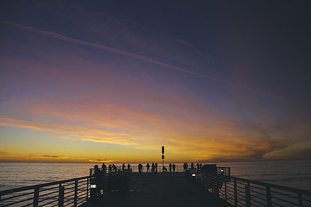 silhouette photo of people on sea aisle during sunset with cirrus cloud formation