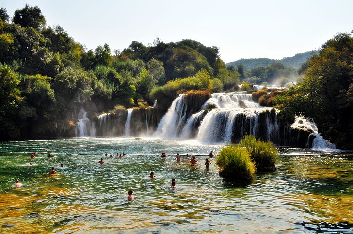 People Swimming Near Waterfall during Daytime