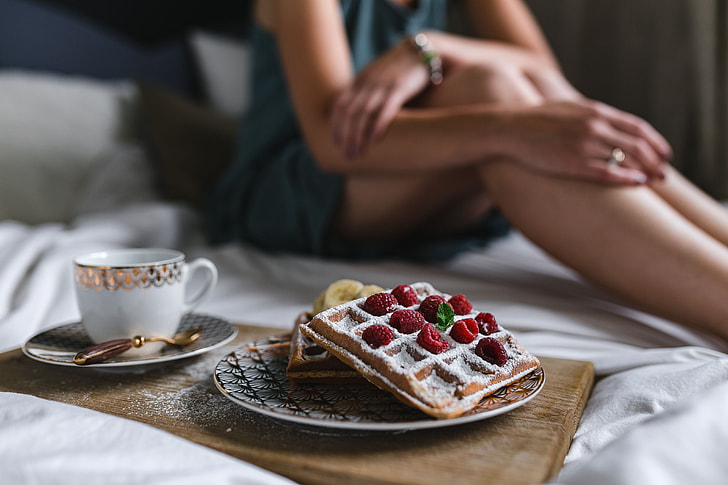Breakfast in bed - waffles with raspberries and cup of coffee on the tray