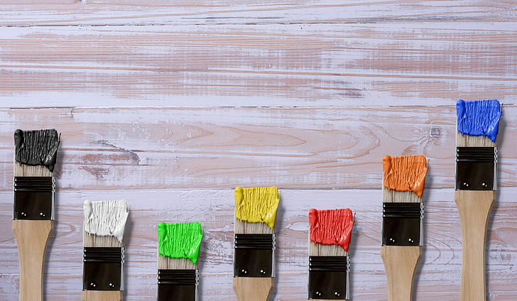 seven brown-and-black paint brushes with assorted-color paints