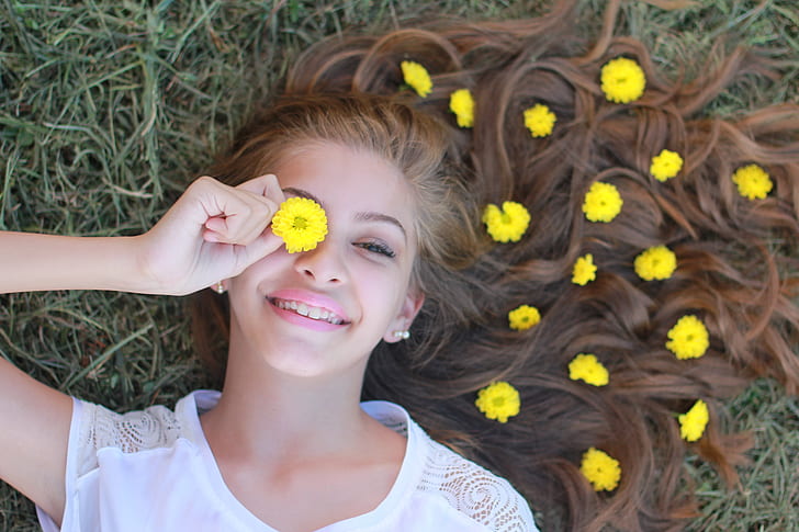 woman holding yellow mums flower in her eye
