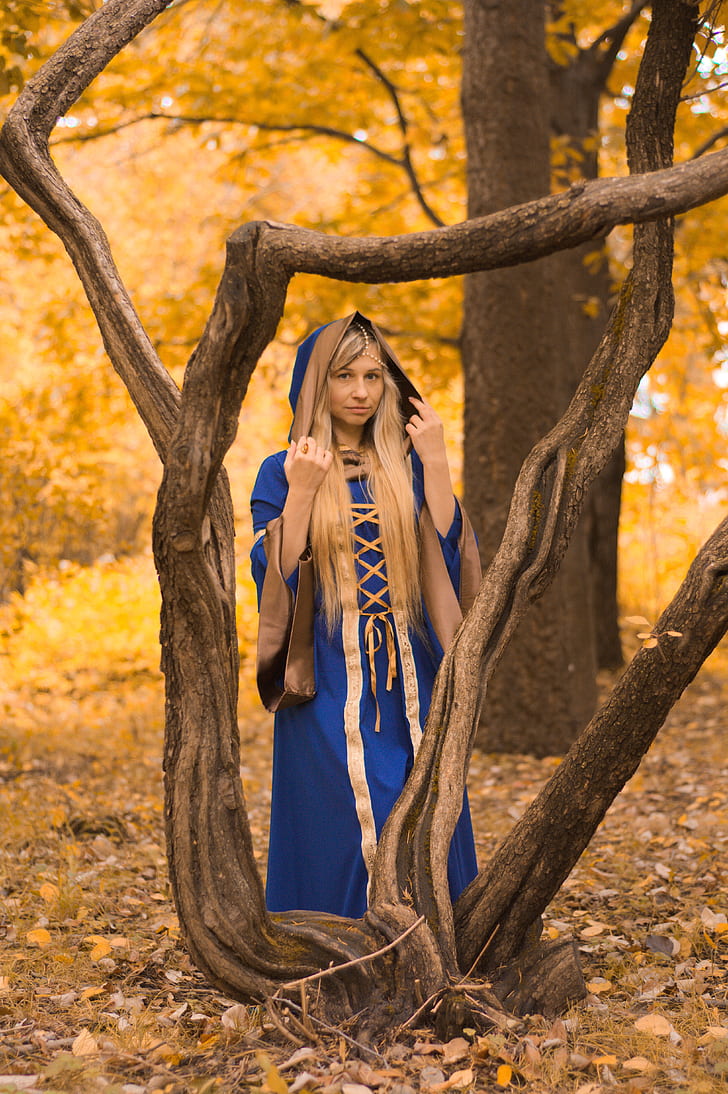 woman wearing blue and gold dress standing beside tree