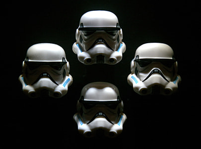 four Star Wars Storm Trooper helmets on black background