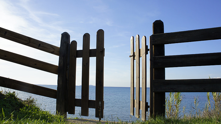 brown wooden gate opened near seashore at daytime