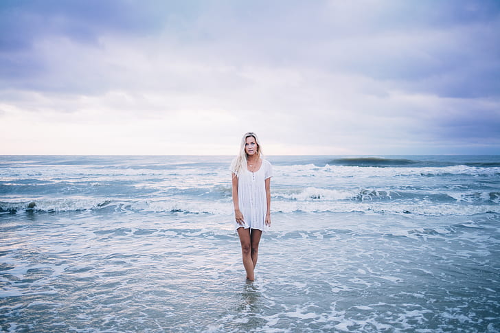 woman with white hair in white dress standing on seashore