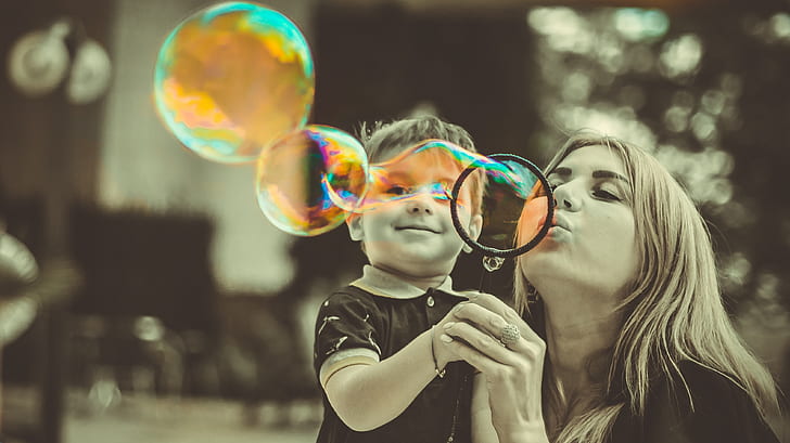 woman wearing black top with her child playing with bubbles