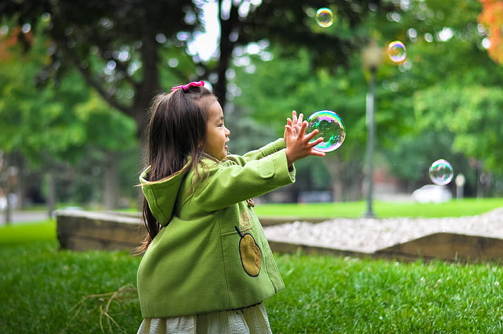 girl playing bubbles in green grass field