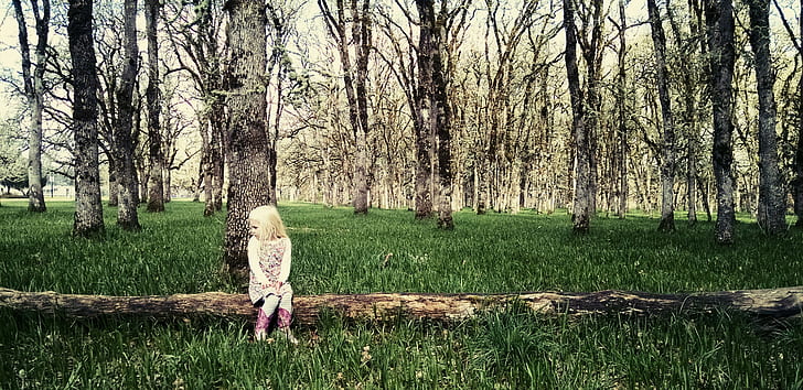 girl sitting on tree log with surrounded by trees
