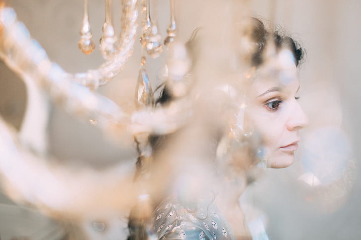 selective focus photography of woman behind chandelier