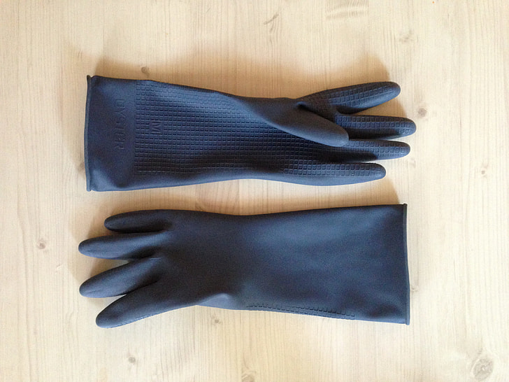 pair of black rubber gloves on beige wooden surface