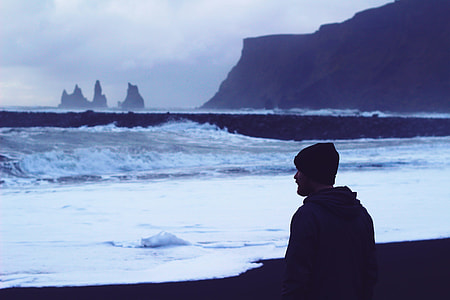 man wearing knit cap and jacket near body of water