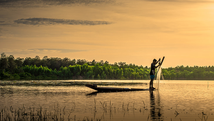 man on boat holding fish net