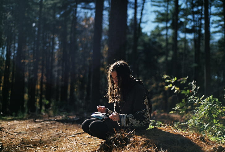 woman sitting on brown grass holding book