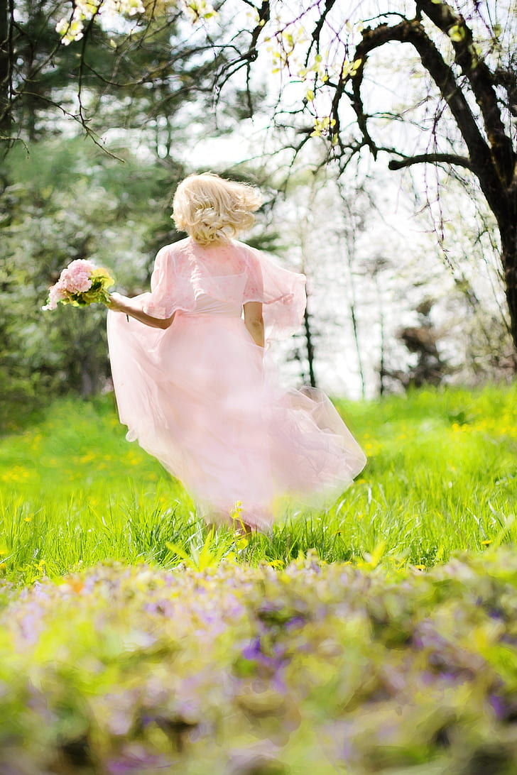 woman in pink chiffon dress holding pink of flower bouquet running at daytime